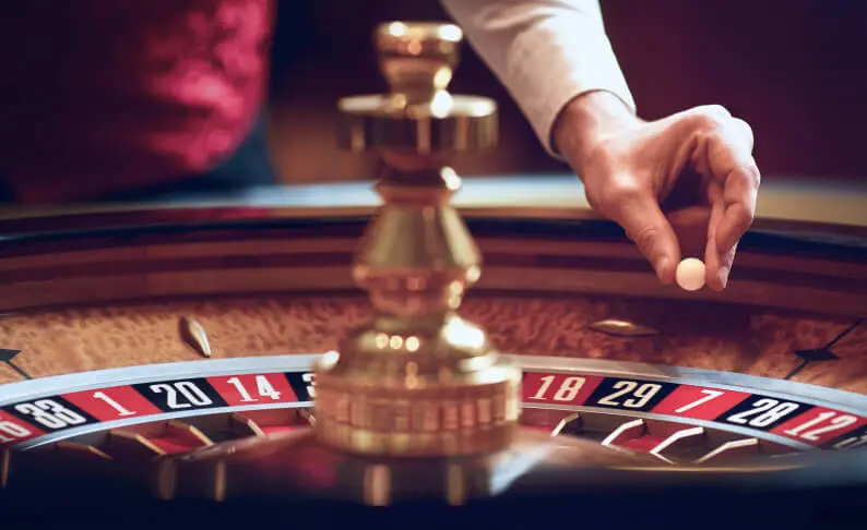 An example image of a roulette dealers hand holding the white roulette ball about to spin the wheel. 